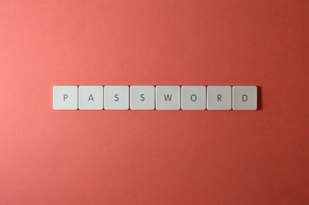 Focus on password security with white keyboard tiles spelling 'PASSWORD' on a coral background.